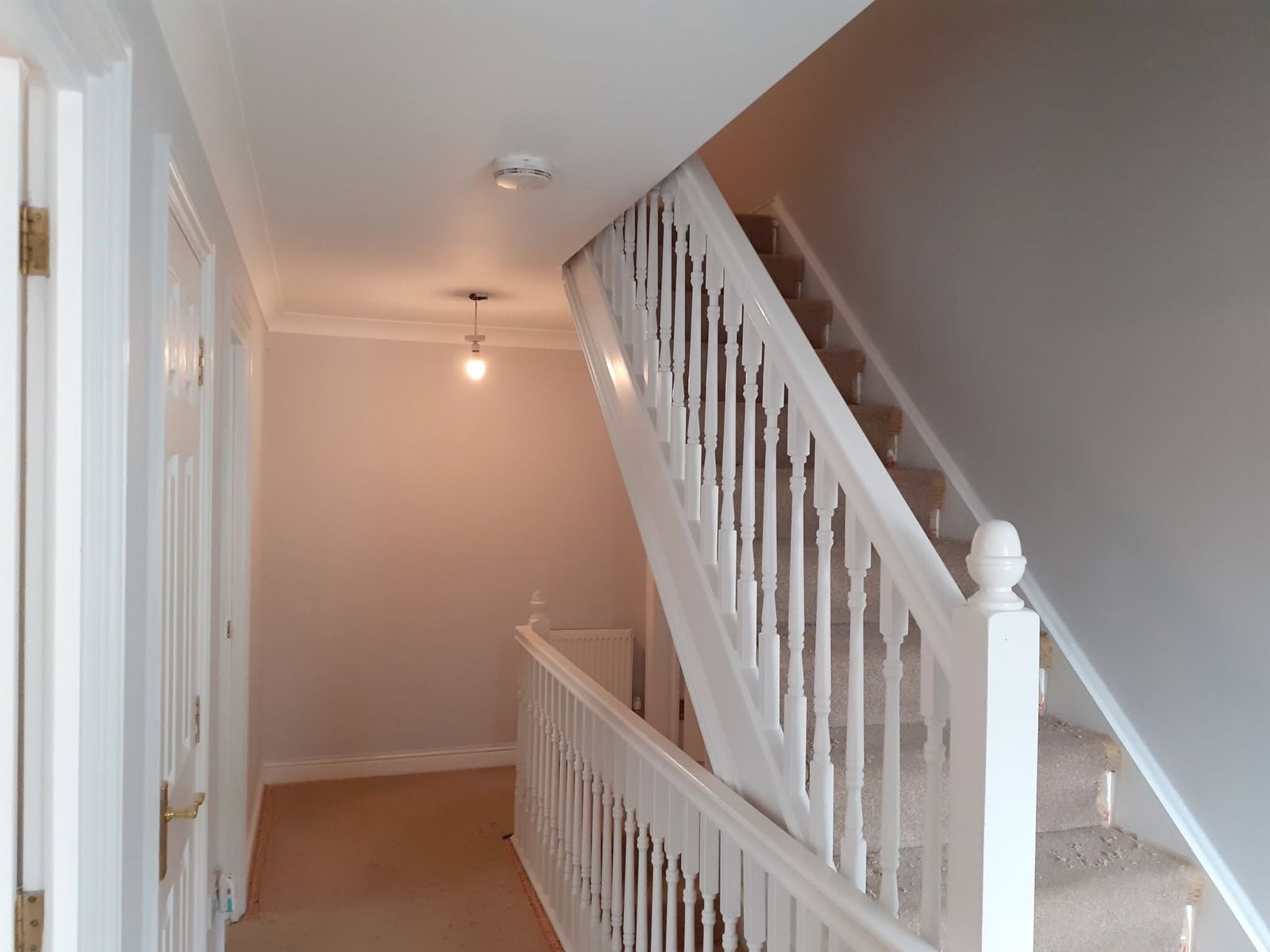 Landing and white staircase with soft pink walls