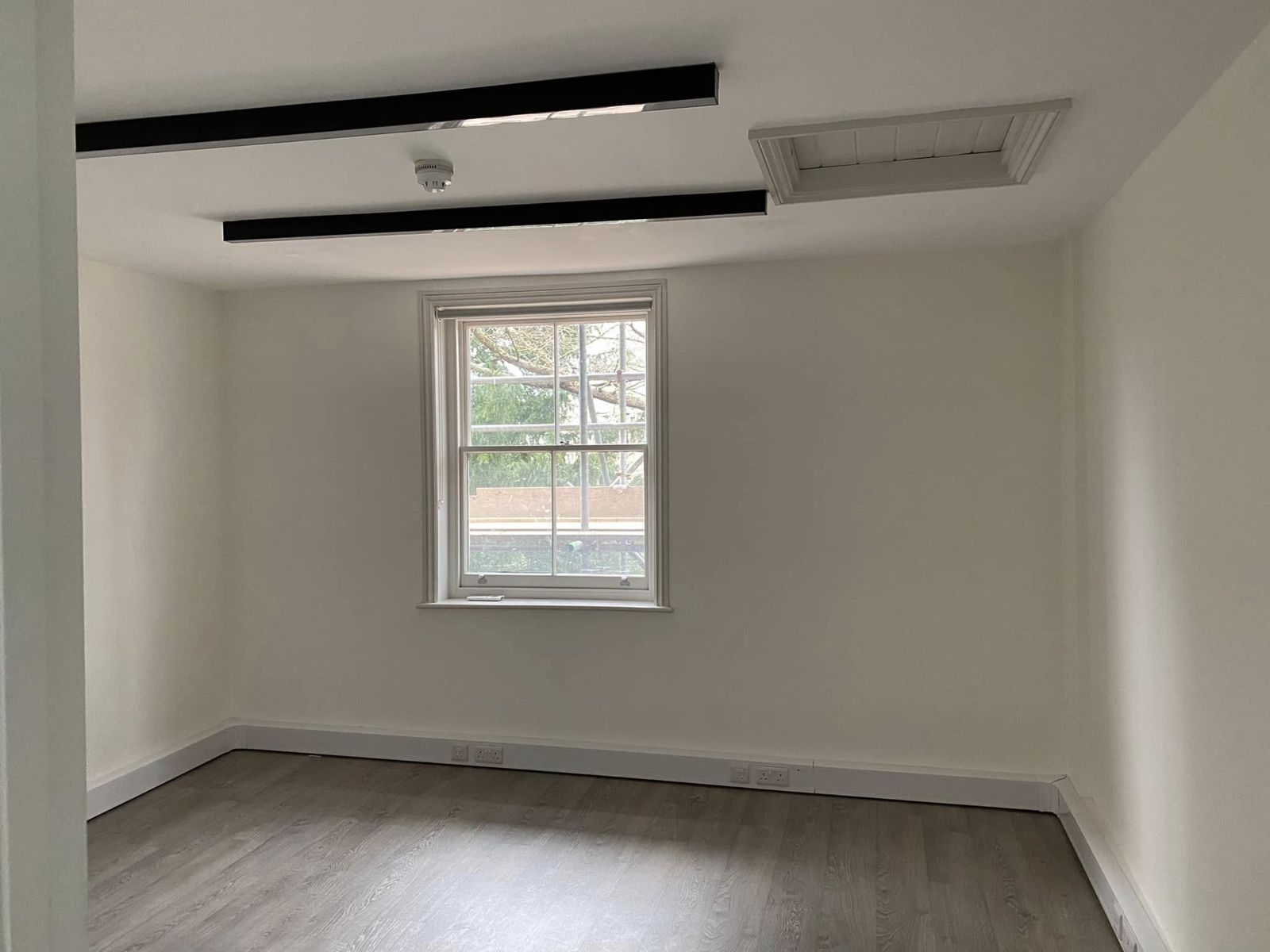 White room with a sash window and wood-effect floor