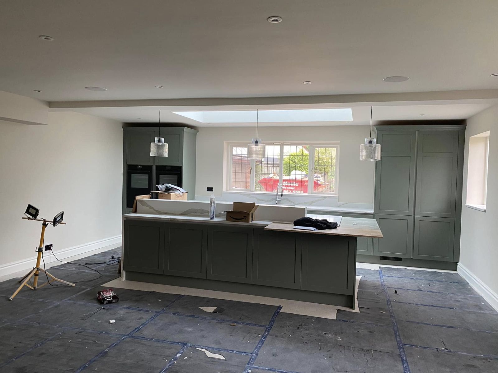 Kitchen with sage-green units and island under freshly painted walls