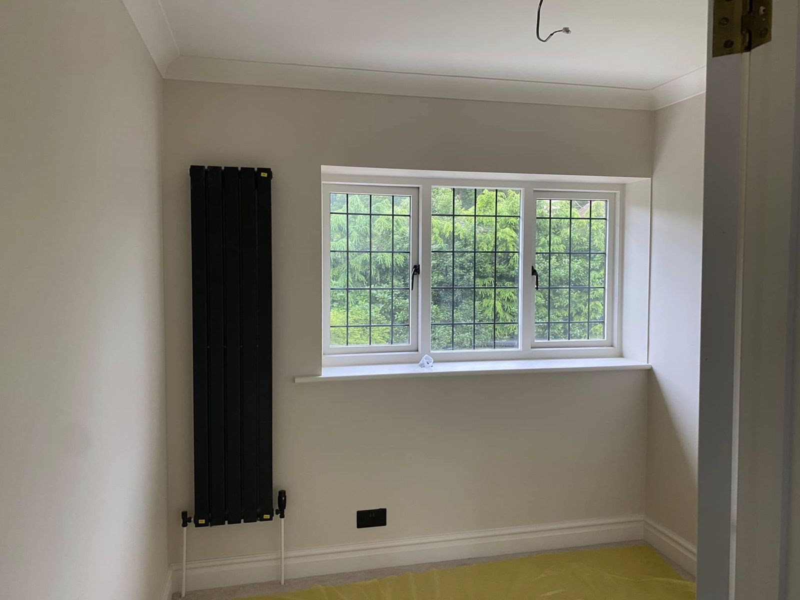 Room with a black column radiator and a leaded bay window