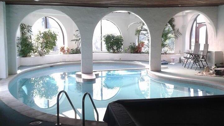Indoor swimming pool room with white arched columns