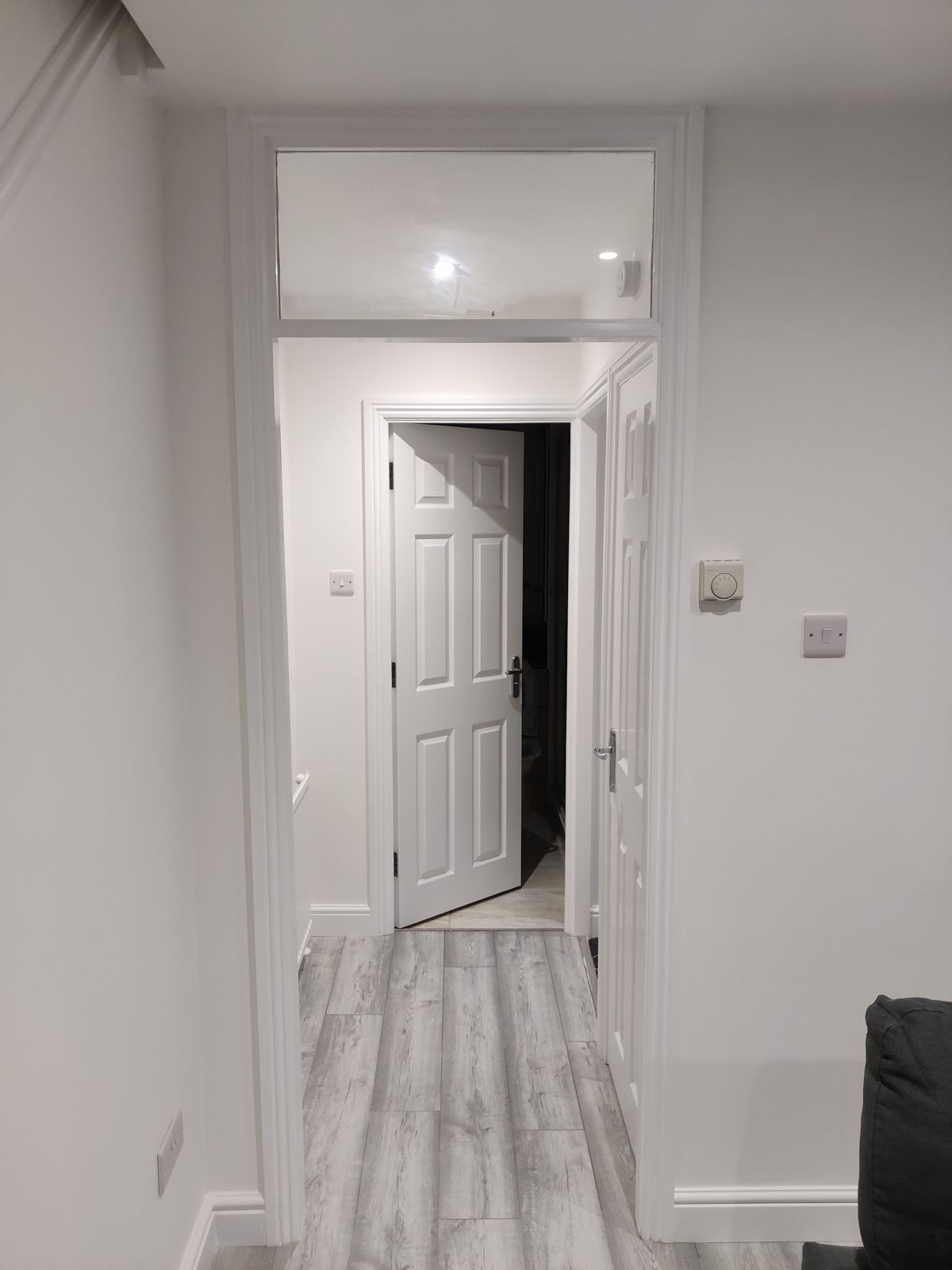 White hallway with doors and a pale wood-effect floor