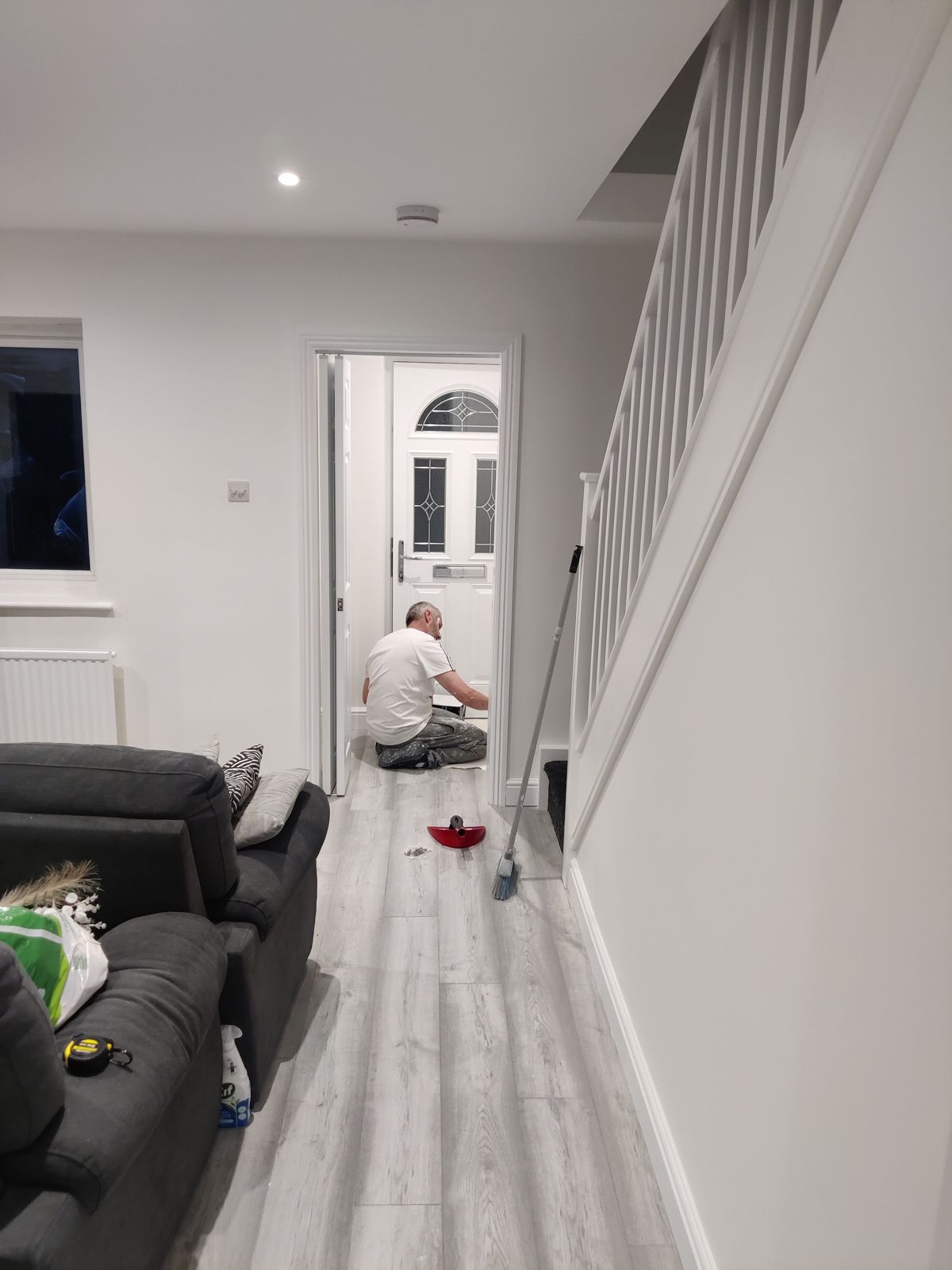 Painter kneeling at work by the staircase in a white living room