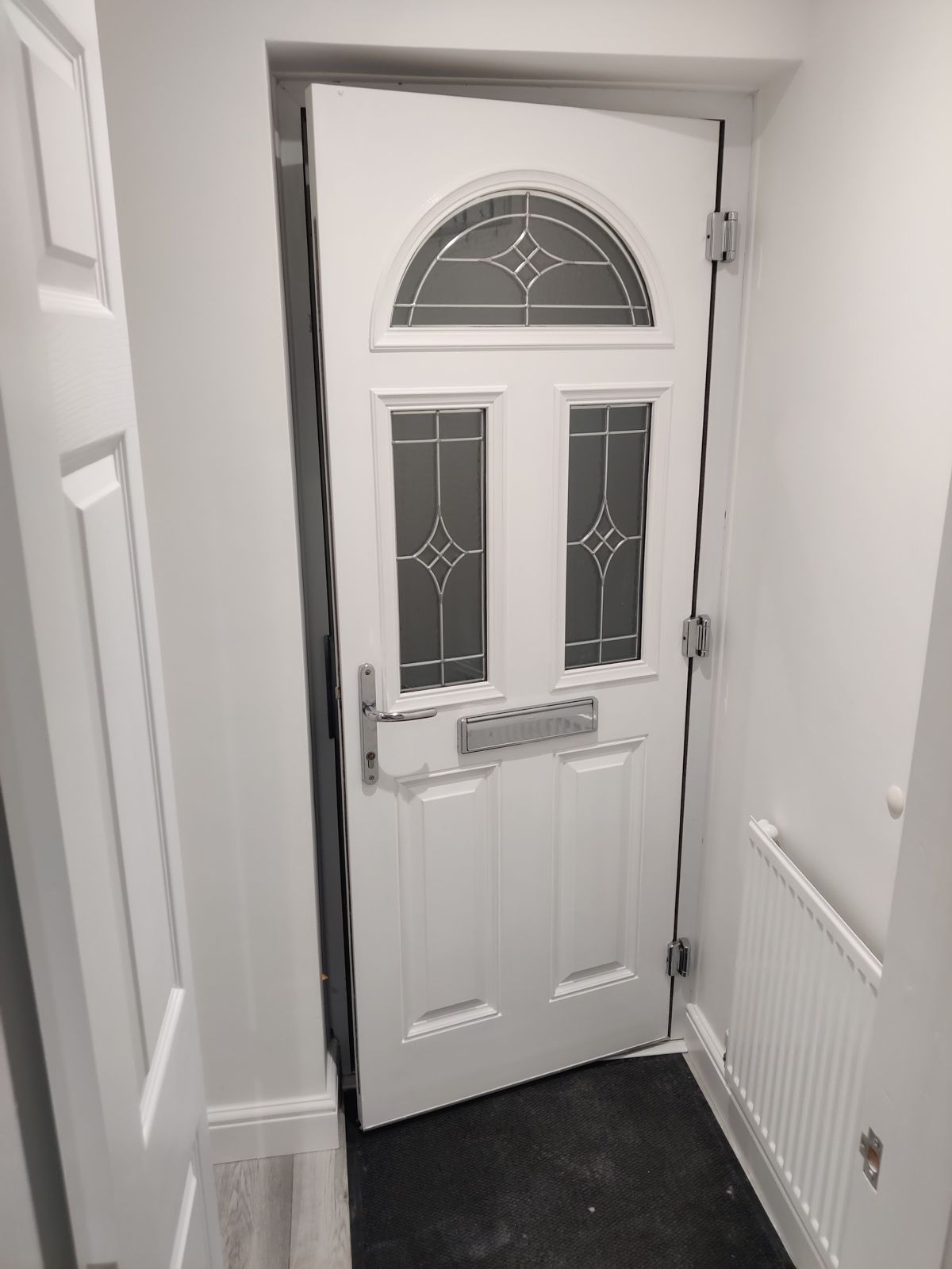 White front door with leaded glass in a freshly painted hall